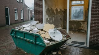 Open container vol badkamertegels en een wasbak voor een uitgehaalde badkamer